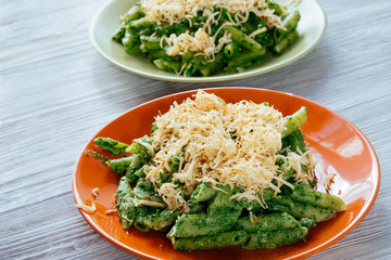 Two plates with spinach pasta and cheese on a white wooden table