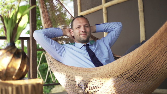 Happy businessman relaxing on hammock on terrace
