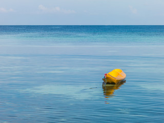 Yellow kayak, clear blue sea and sky background