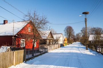 Drewniane wiejskie chaty przy drodze zasypanej śniegiem - obrazy, fototapety, plakaty