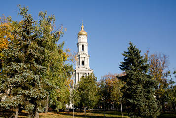 Cathedral of the Assumption, surrounded by coniferous and deciduous trees on the background of a cloudless autumn sky. Kharkov, Ukraine. A horizontal view