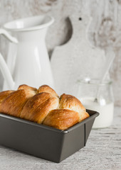Homemade bread brioche in the baking dish on a light rustic wooden background
