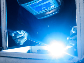 Skilled worker welding metal together in a welding factory
