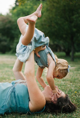 Happy young hipster family having fun while running, bowl,  rising up, piggyback ride their children in park on summer sunset
