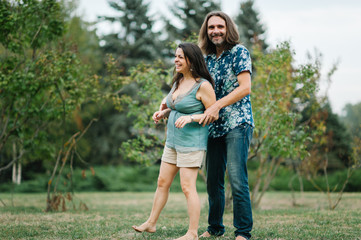 Fototapeta premium Happy young hipster family hug each other in park on summer sunset 