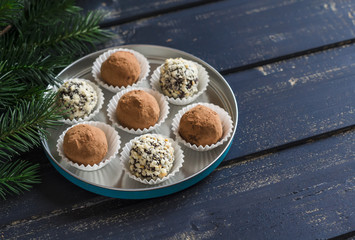 Assorted homemade candy - dark chocolate truffles with nuts and cocoa on dark wooden surface