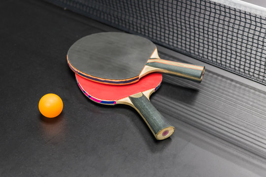 table tennis racket with  ball on black table