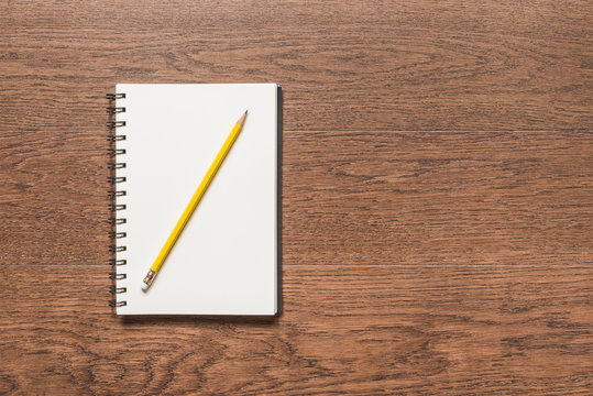 yellow pencil with blank note book on wooden background
