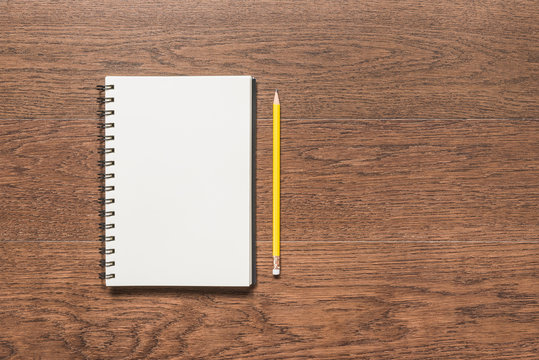 yellow pencil with blank note book on wooden background