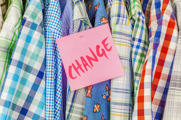 Row of hanging shirts with inscription CHANGE on paper sticker
