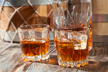 Two glasses of whiskey with ice and decanter