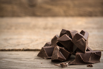 Pieces of chocolate bar on wooden background