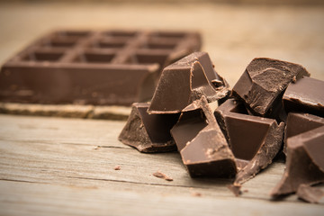Pieces of chocolate bar on wooden background