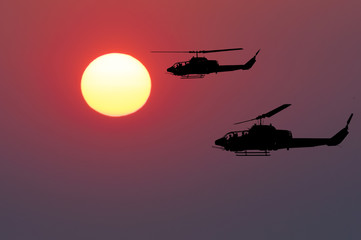Fototapeta na wymiar Two flying army helicopters on sunset background