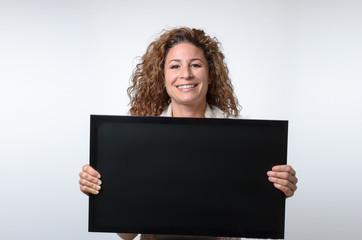 Naklejka premium Young woman holding up a blank monitor