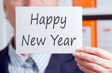 Happy New Year - Manager holding sign with text in the office