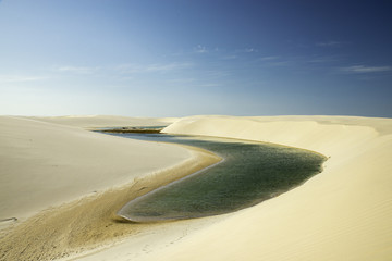 Fototapeta na wymiar Lagoon in desert white sand dunes of the Lencois Maranheses National Park, Brazil.