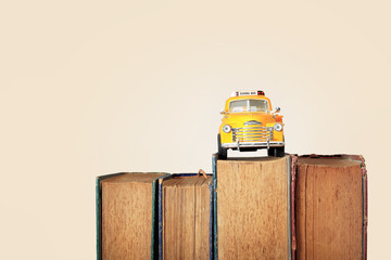 Yellow school bus toy model and old books.Vintage background.