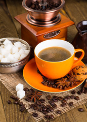 Coffee cup and coffee beans on a wooden table and sack backgroun