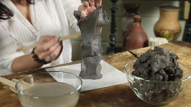 Sculptor woman shapes the clay with hands close-up
