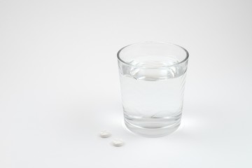 pills and a glass of water isolated on a white background