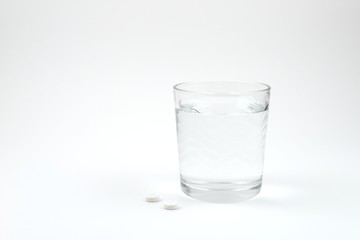 pills and a glass of water isolated on a white background