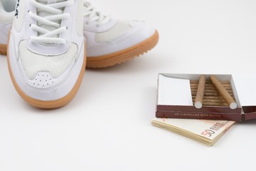 Fototapeta na wymiar sport shoes, Euro and cigarettes, concept of healthy lifestyle