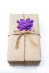 Gift box package wrapped with paper and rope with purple flowers on a white background