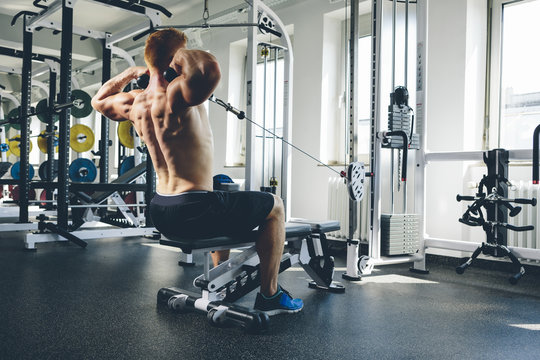 Physical athlete exercising with cable machine