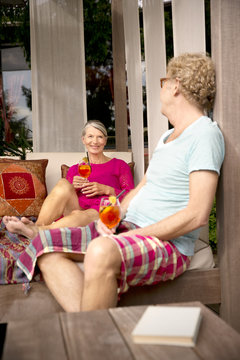 Smiling senior couple sitting on lounge outdoors with cocktails