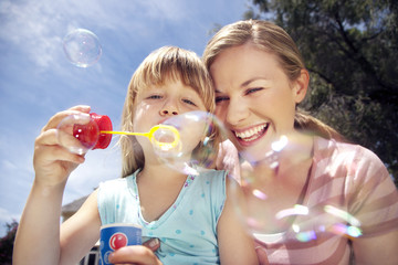 Woman and her little daughter blowing soap bubbles