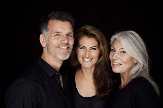 Portrait of three smiling people in front of black background