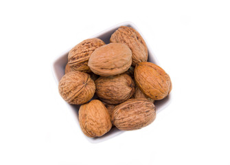 Walnuts on square bowl on a white background seen from above