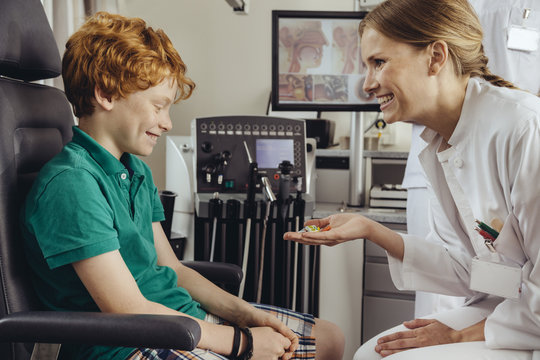 Female doctor giving child patient candy after successful screening in ENT practice
