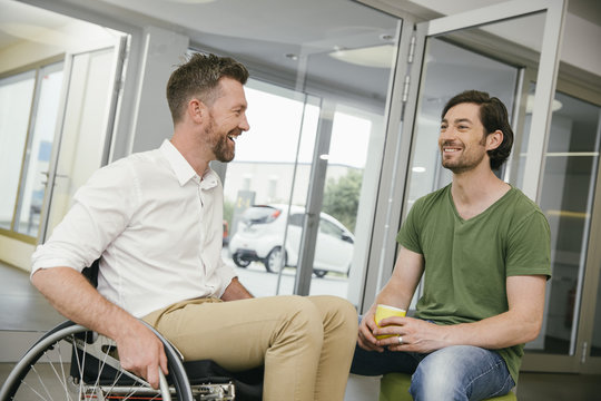 Man in wheelchair talking to colleague