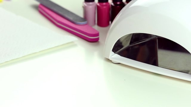 Manicure in process - putting hand and curing gel varnish in nail LED lamp, procedure of polymerization