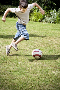 Little boy playing soccer in the garden
