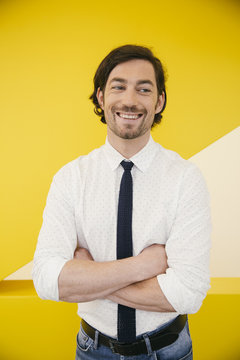 Portrait of smiling mature man wearing shirt and tie standing in front of a yellow wall