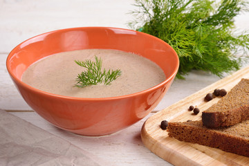 Cream of mushroom soup with dill in an orange cup closeup