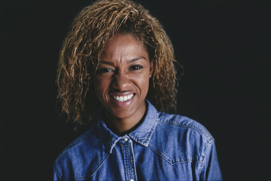 Portrait of woman wrinkling nose in front of black background
