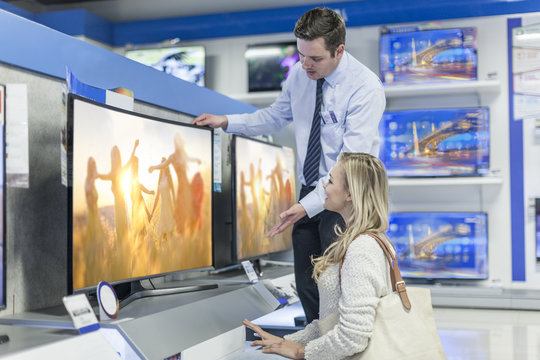 Shop assistant showing flat screen TV to customer