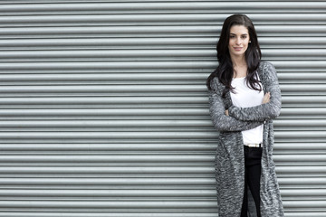 Portrait of young woman with crossed arms standing in front of roller shutter