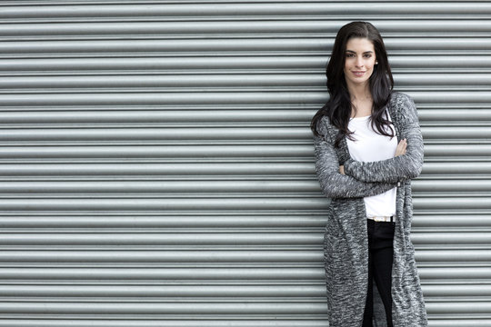 Portrait of young woman with crossed arms standing in front of roller shutter