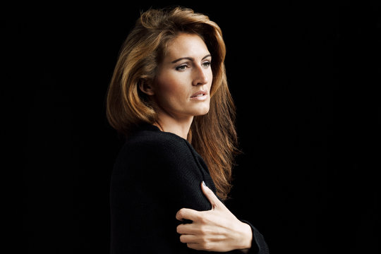 Portrait of pensive woman with brown hair in front of black background