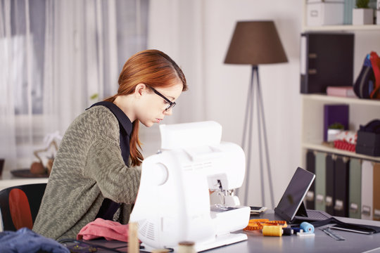 Portrait of young woman using sewing machine at home