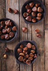 Chestnuts in a cast iron skillet on wooden background.selective focus.