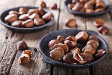 Chestnuts in a cast iron skillet on wooden background.selective focus.