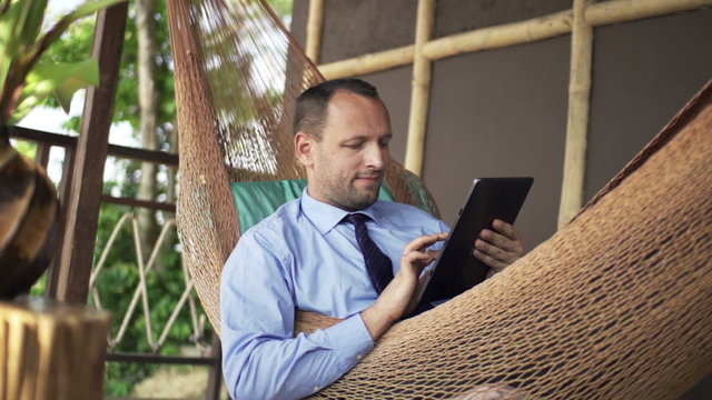 Businessman with tablet computer on hammock on terrace, super slow motion 240fps
