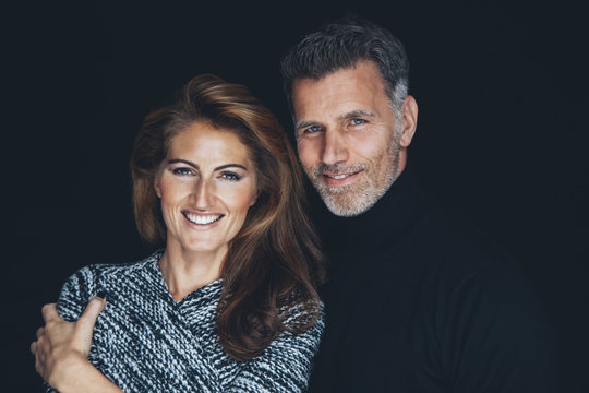 Portrait Of Smiling Couple In Front Of Black Background