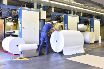 Man moving paper roll in a printing shop